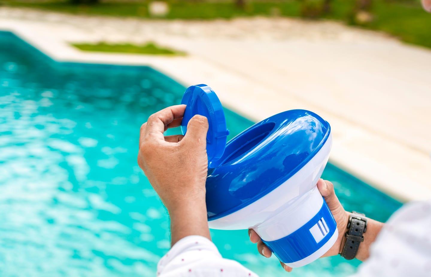 Pool service business technician's hands installing a chlorine dispenser float — daily hands-on work in a residential pool service route